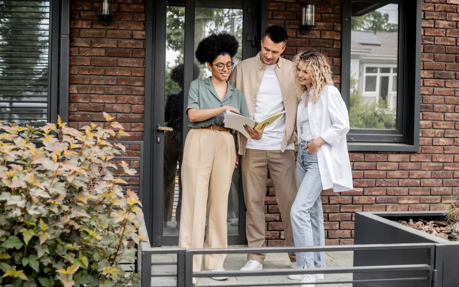 Three people reviewing investment property paperwork on the front steps of a Lehigh Valley home